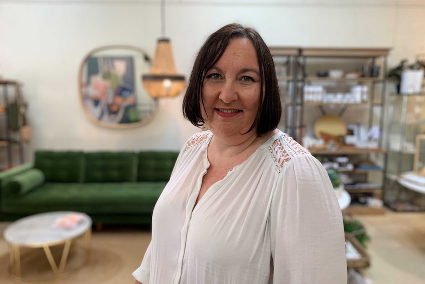 Woman in homewares shop, with furniture, light, mirror in background