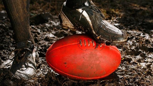 Footballer stands in mud, foot rests on football