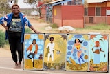 Artist Kaylene Whiskey stands outside an arts centre in Indulkana with a painting.