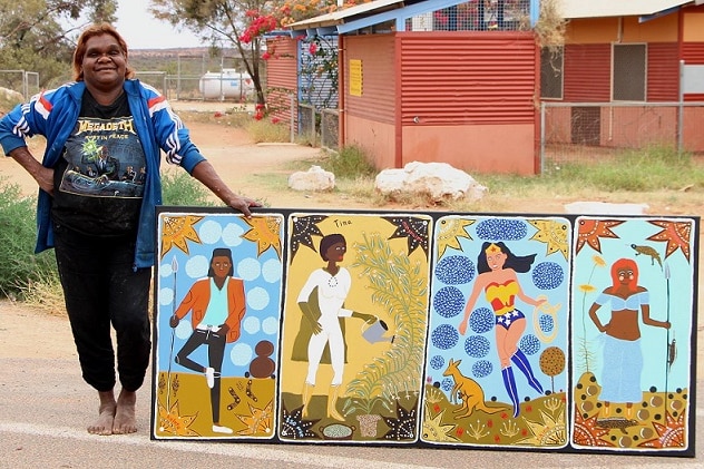 Artist Kaylene Whiskey stands outside an arts centre in Indulkana with a painting.