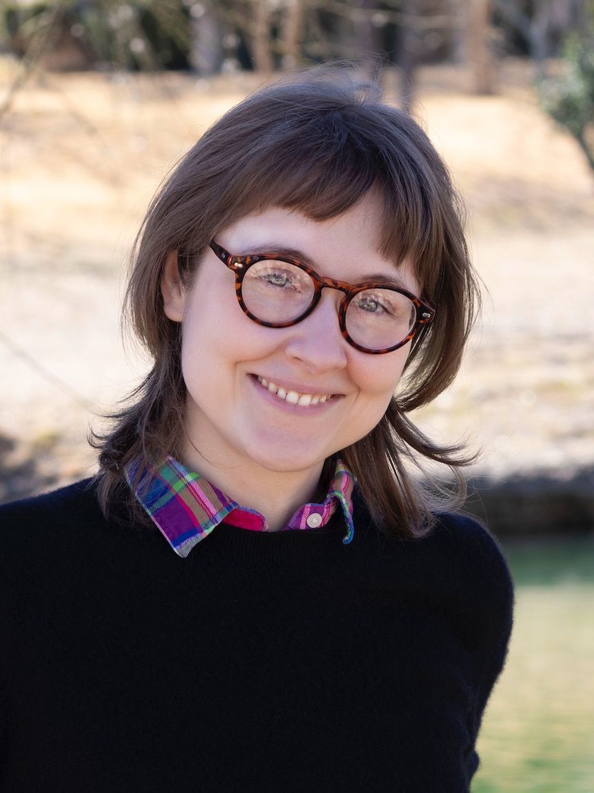 Dr Olivia Walch is pictured with glasses, a plaid shirt and jumper