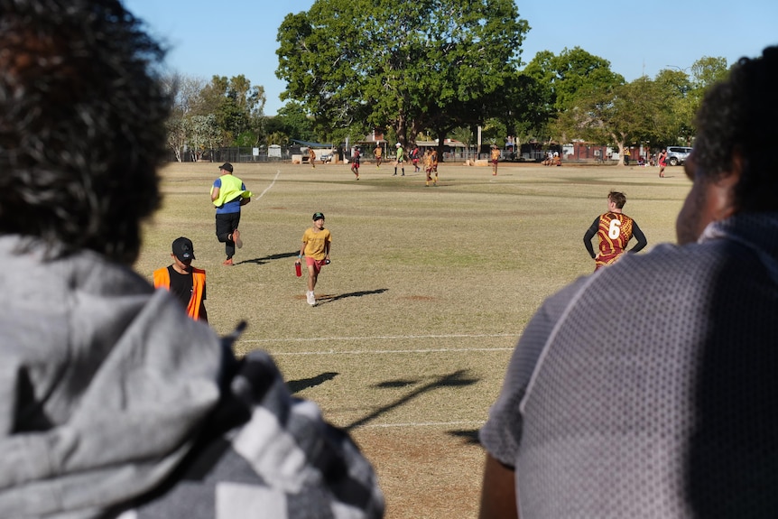 two out of focus spectators watch a country football game