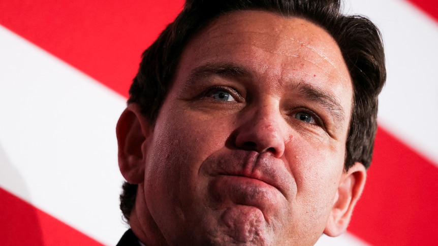 A close up of Ron DeSantis frowning at a campaign event.