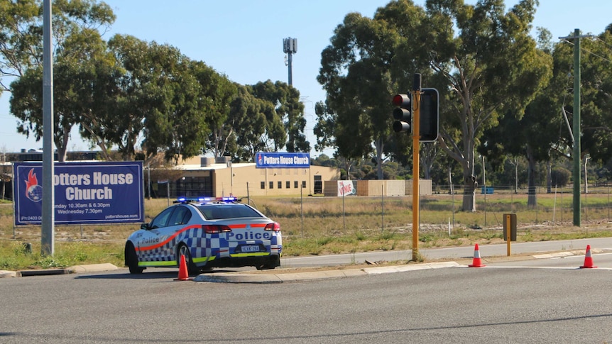 A police car and witches hats block Beechboro Road North, near the entrance to the Potter House Church.