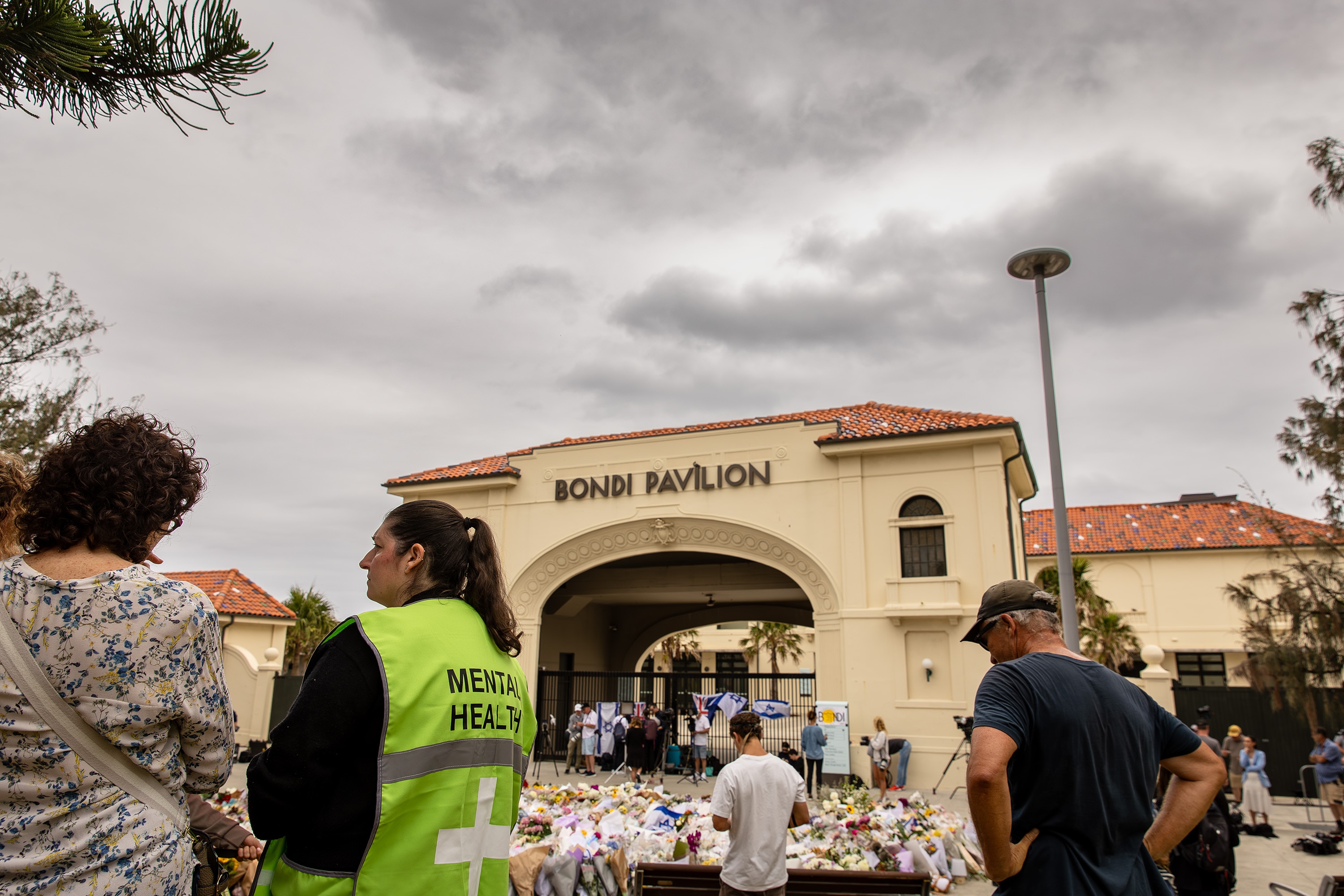 Uma mulher com um colete neon que diz Saúde Mental fala com outra mulher fora do pavilhão Bondi