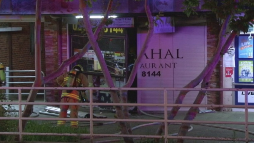 A fireman stands outside the Raj Mahal restaurant in Windsor at night, after it was damaged by fire.