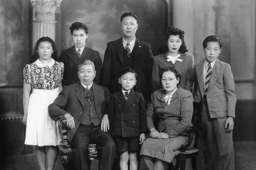 A black and white family portrait of the O'Hoy family comprising two young girls and three boys with their parents