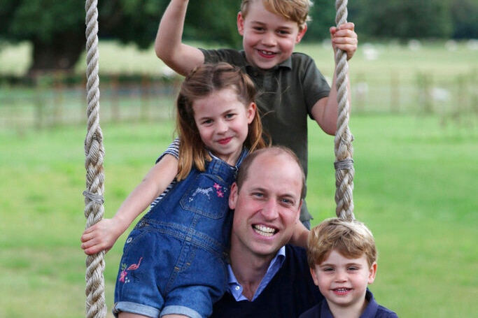 Prince William and his three children on a swing.