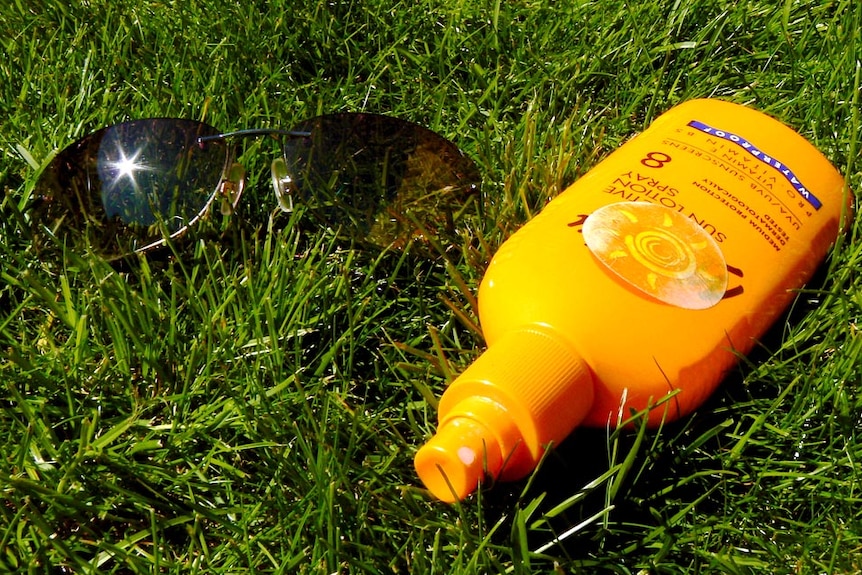 Close-up of sunscreen bottle and sunglasses on the grass, April 2012.