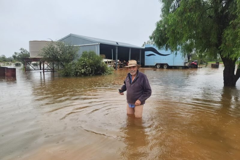 Flooding at an outback pastoral station with a man standing in the water in his underwear.  