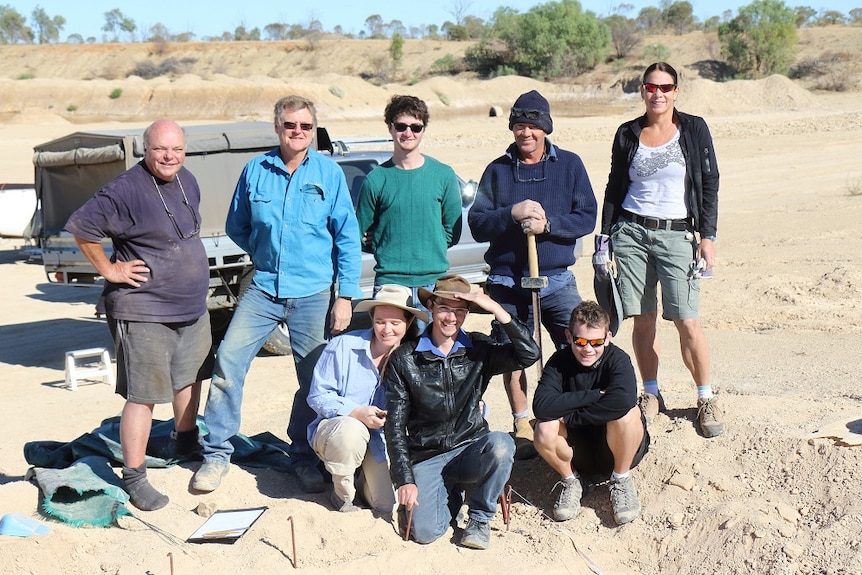 Group of volunteers standing at dig site.