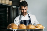 Pastry chef Will Jane inspects four sourdough loaves in his kitchen.