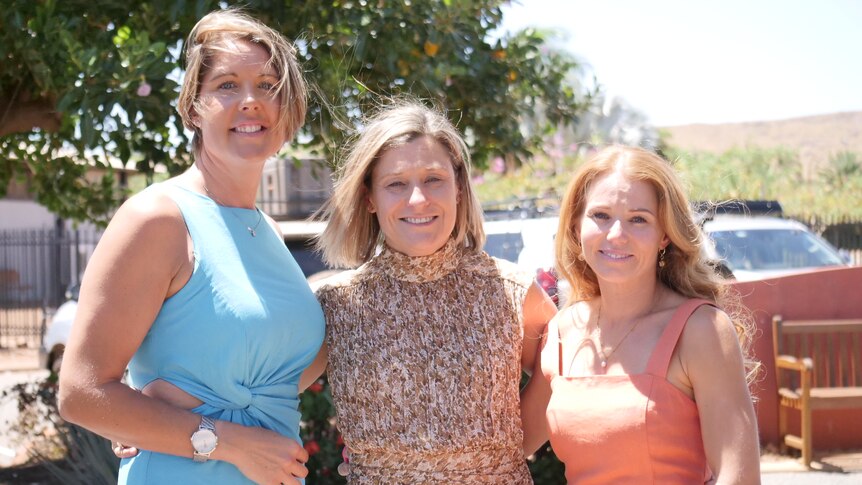 three women stand side by side smiling at the camera