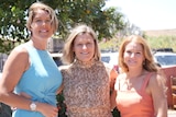 three women stand side by side smiling at the camera