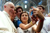 Pope Francis poses with youth in the Church of Saint Augustine in downtown Rome.