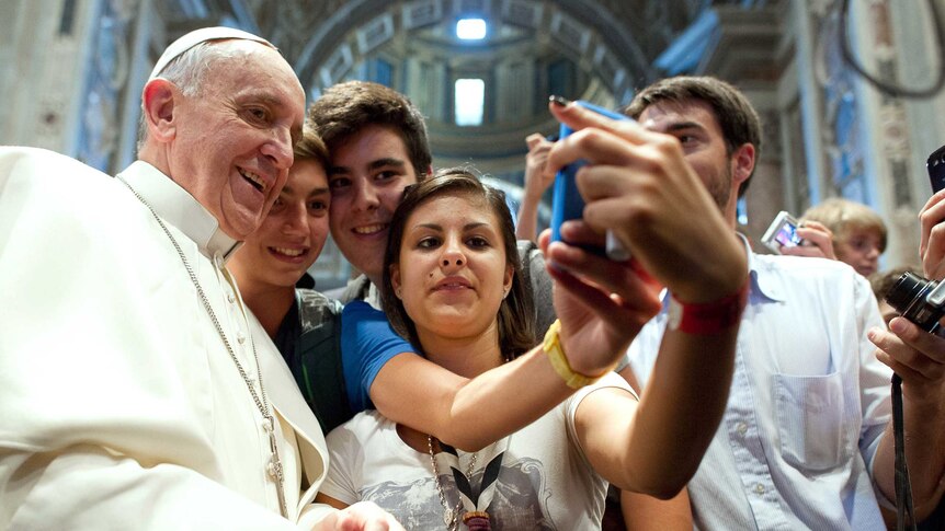 Pope Francis poses with youth in the Church of Saint Augustine in downtown Rome.