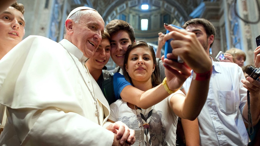 Pope Francis poses with youth in the Church of Saint Augustine in Rome.