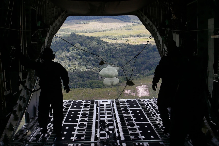 food packages are parachuted down from a military aircraft to be delivered to Yanomami people