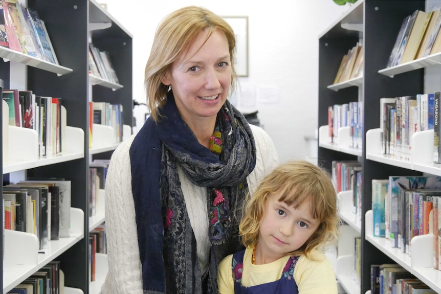 A mum with short, dark blonde hair smiling at the camera, with her daughter on her lap.