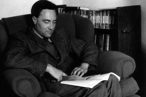 A black-and-white archive shot of David Goodall sitting in a chair reading a book.