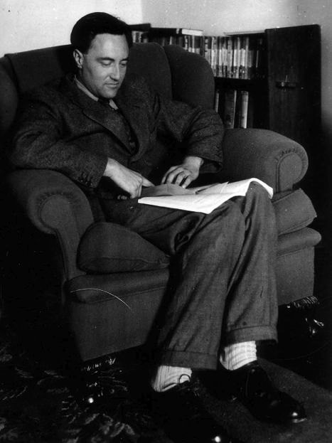 A black-and-white archive shot of David Goodall sitting in a chair reading a book.