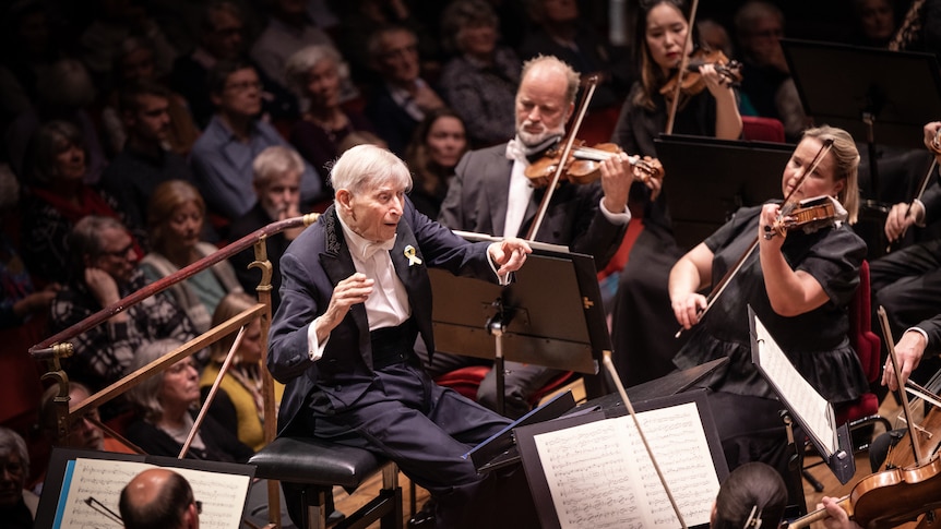 Herbert Blomstedt seated at the podium conducting the Royal Stockholm Philharmonic Orchestra