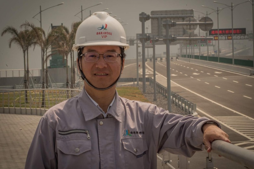 Yu Lie stands in front of the sea bridge.