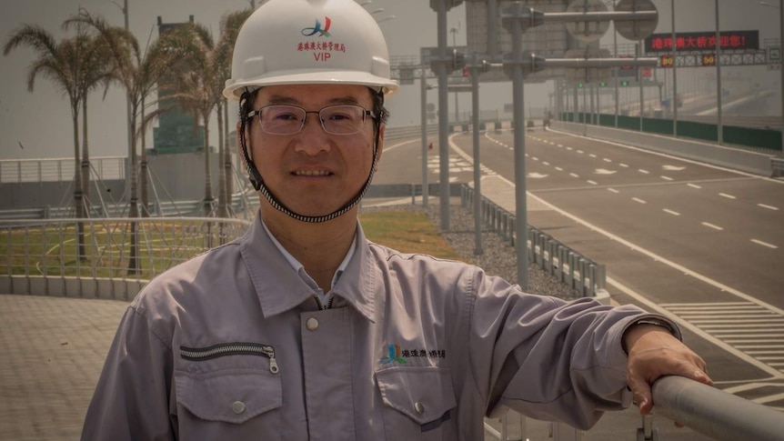 Yu Lie stands in front of the sea bridge.