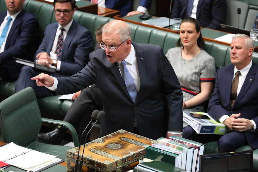 A man talking points across the room as he looks angrily across the House of Representatives.