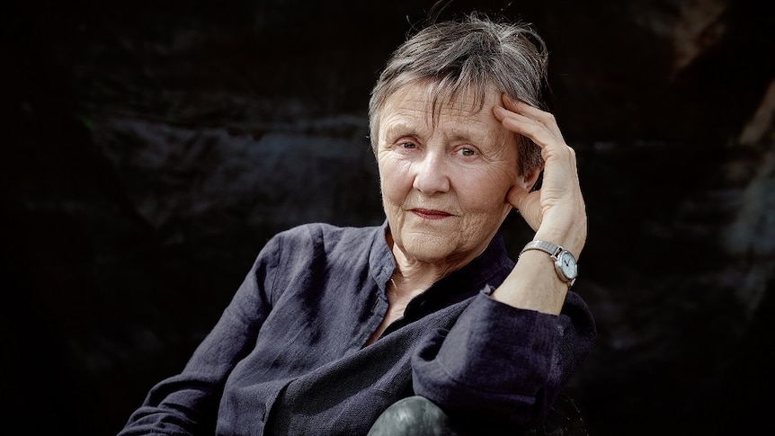 Author Helen Garner, pictured looking solemnly at the camera against a dark background.