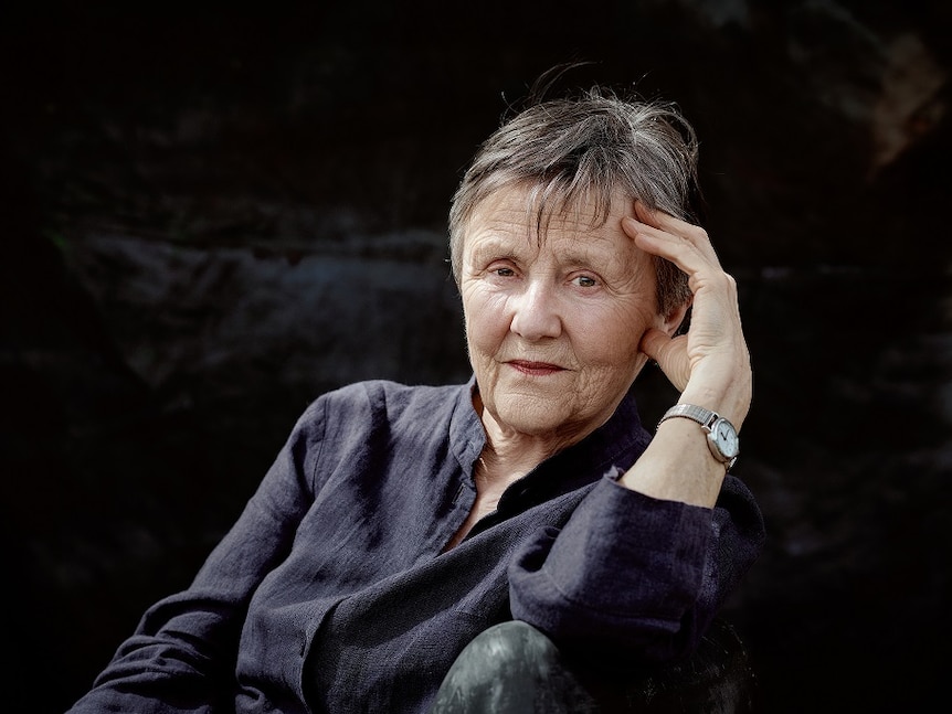 Author Helen Garner, pictured looking solemnly at the camera against a dark background.