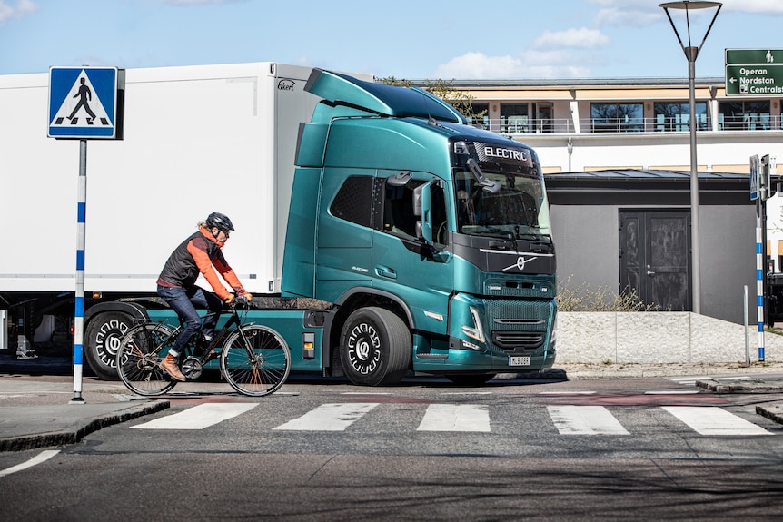 Volvo's prime mover on the road in Sweden near a zebra crossing with a cyclist.