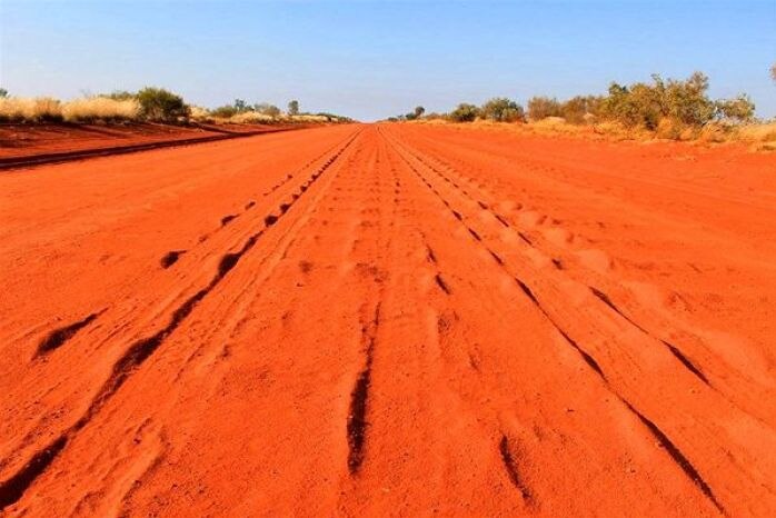 A stretch of dusty red road in the outback.