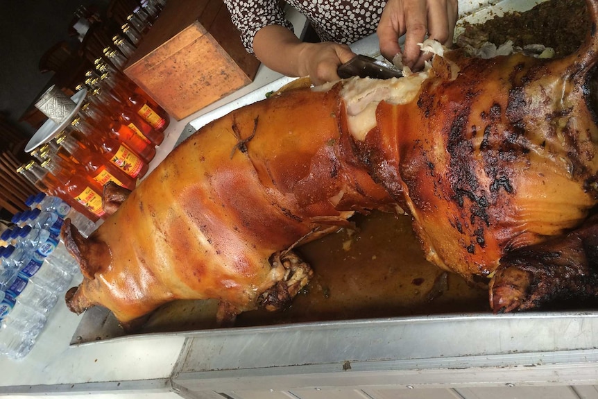 A Balinese pork vendor cuts up suckling pig.