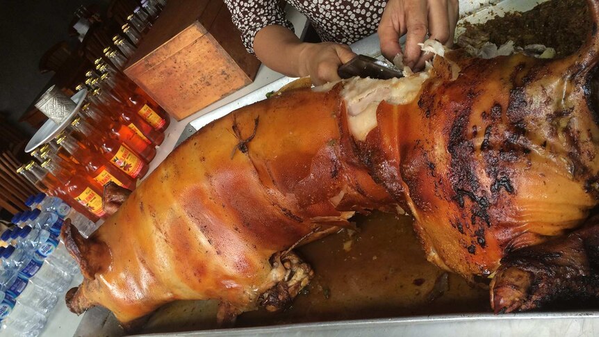 A Balinese pork vendor cuts up suckling pig.