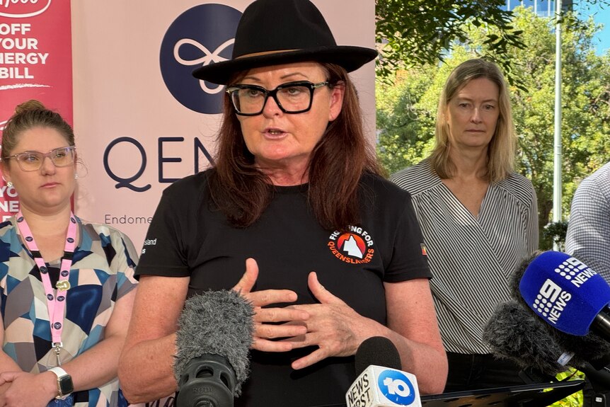 An image of Queensland Unions General Secretary Jacqueline King in front of microphones