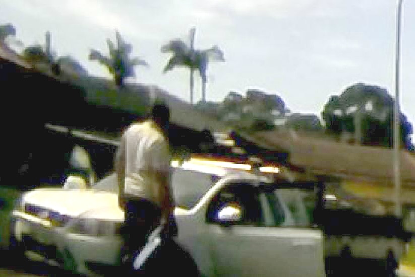 A man standing outside of a white ute which has its front passenger side door open.