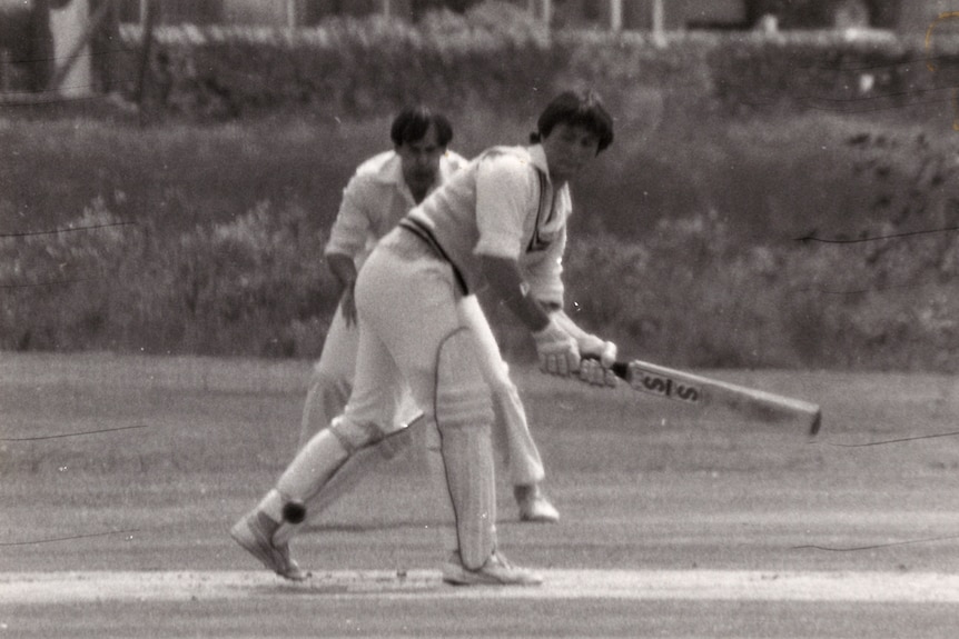 A young ,man playing cricket swings his bat