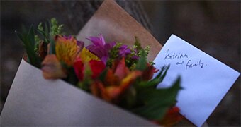 Flowers and a hand written card are placed near the house where seven people were killed.