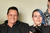 Andy Meddick sits on a couch with his arm around his son, Eden in a family photo.