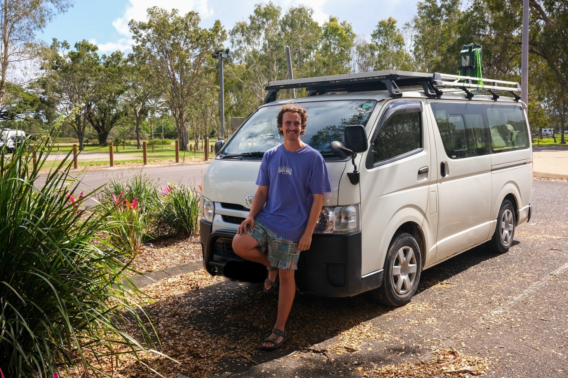 A man leans against the front of a white van.