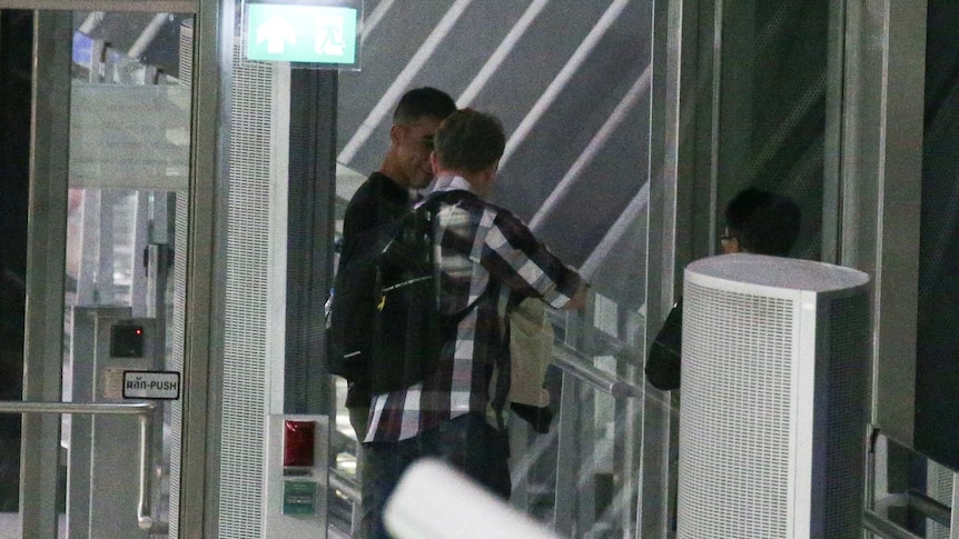 Two men seen at a boarding gate of an airplane.