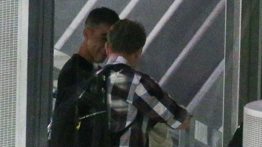 Two men seen at a boarding gate of an airplane.