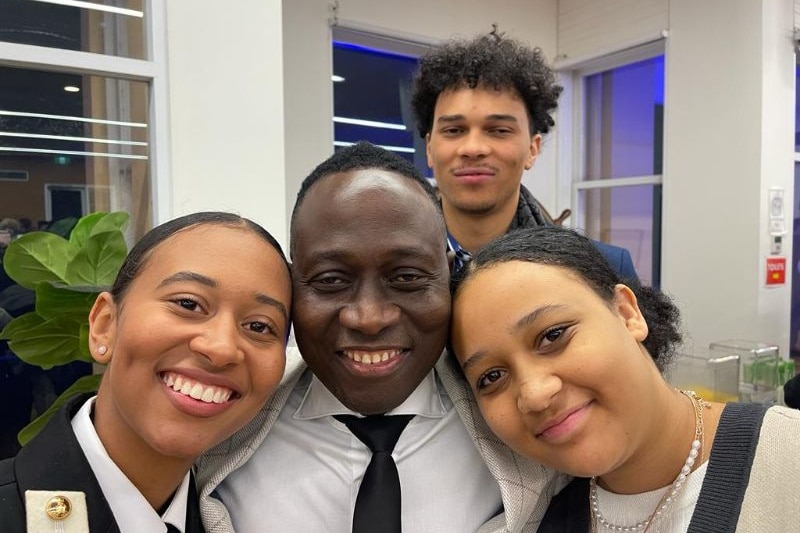 A smiling selfie of three teenagers and a man.
