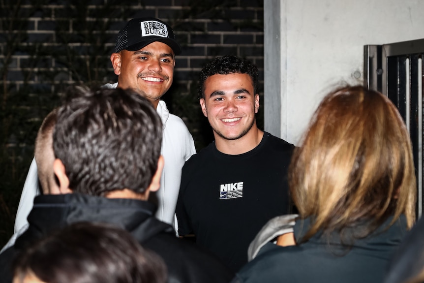 Deux hommes debout côte à côte en souriant pour une photo