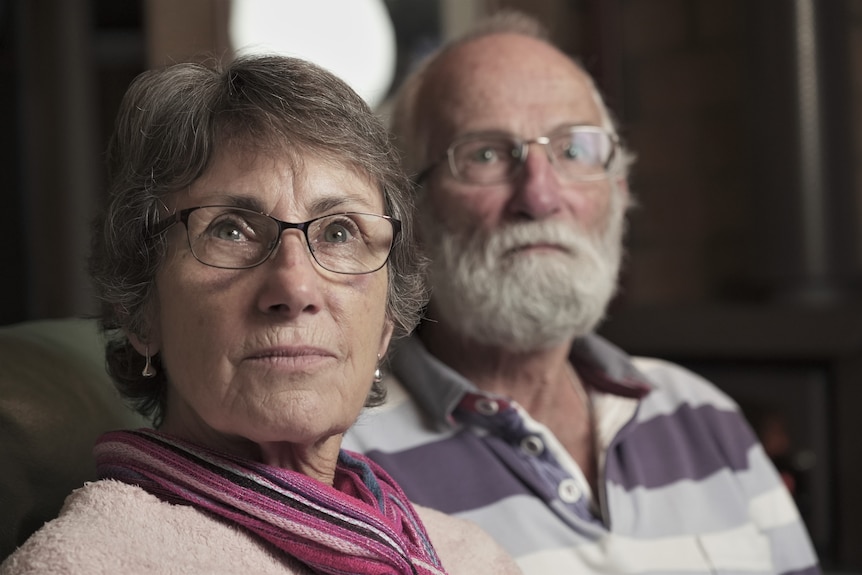 A woman and man sit next to each other on a sofa.