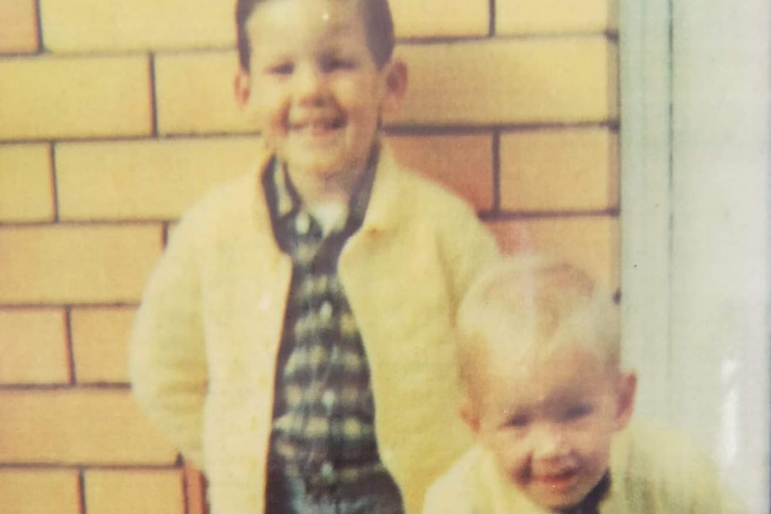 Two young boys standing together in an old photo.