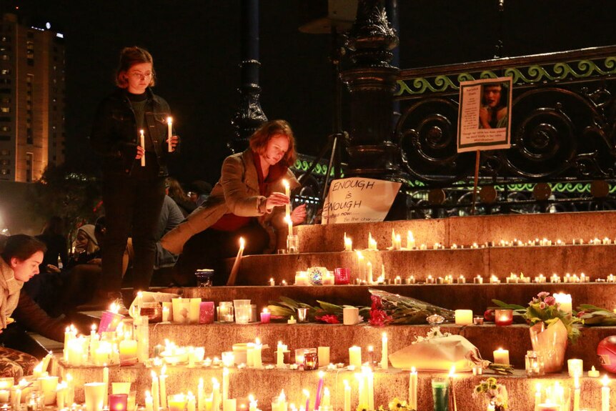 Women place candles at a vigil for Eurydice Dixon, being held in Adelaide.