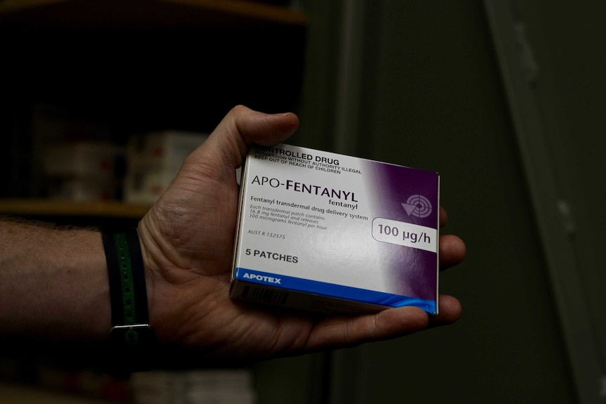 A hand holds a fentanyl packet