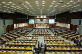 Indonesia's Parliament building in Jakarta. There is a stage at one end with a series of rows of tables.
